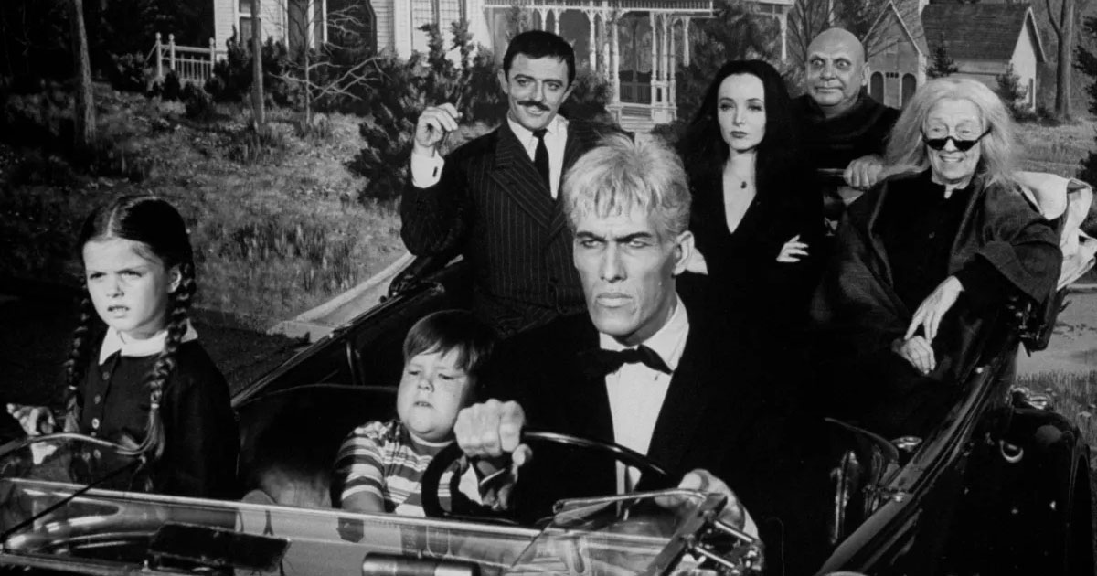 The cast of the 1964 series of the Addams Family driving in a car.